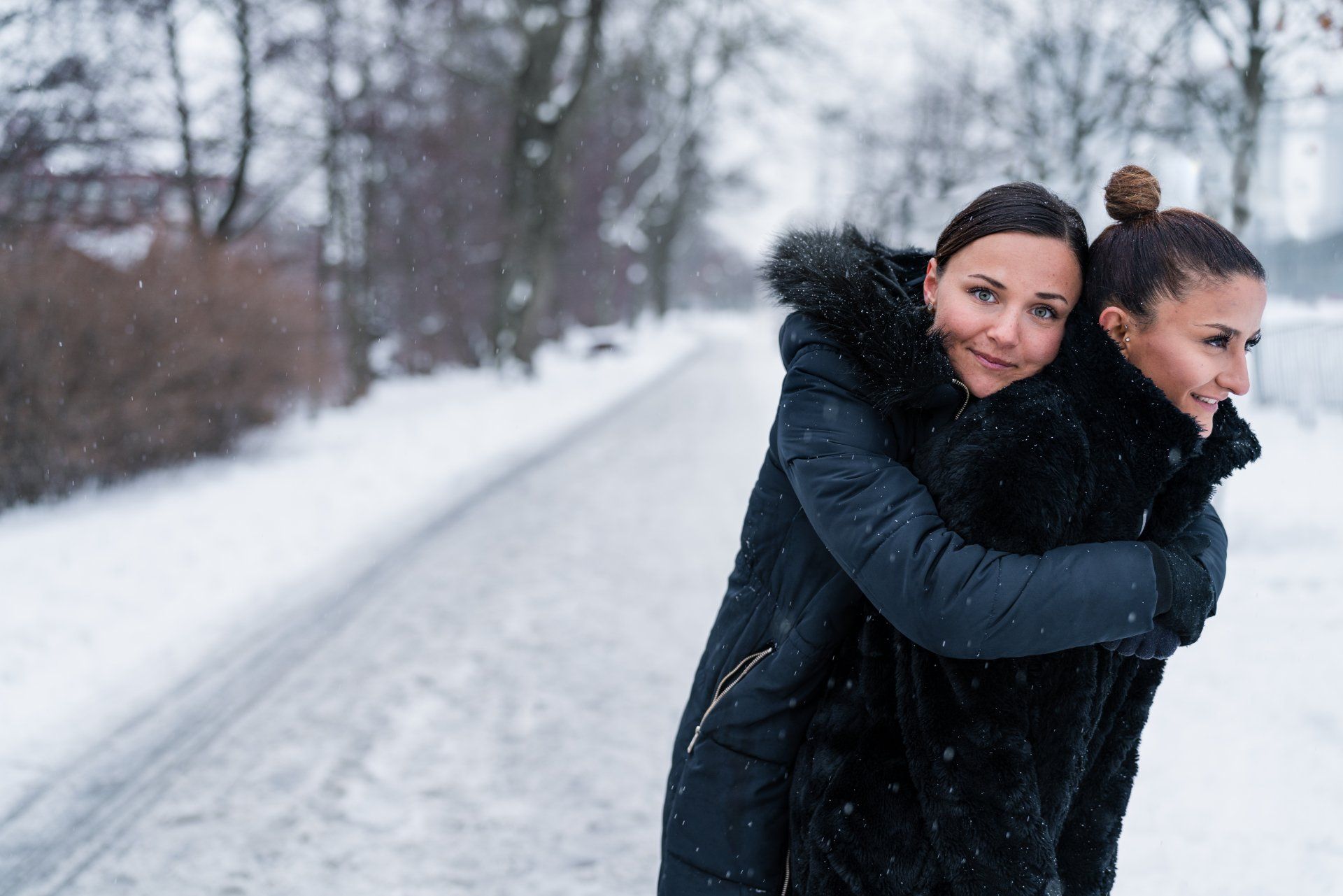 Two women are hugging each other in the snow.