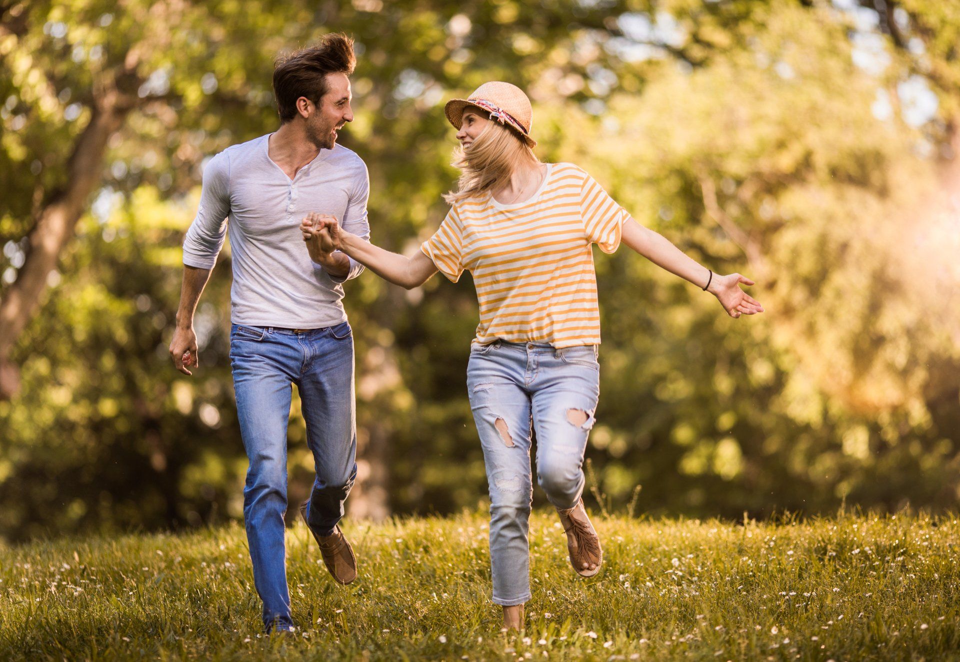 A man and a woman are running in a park holding hands.