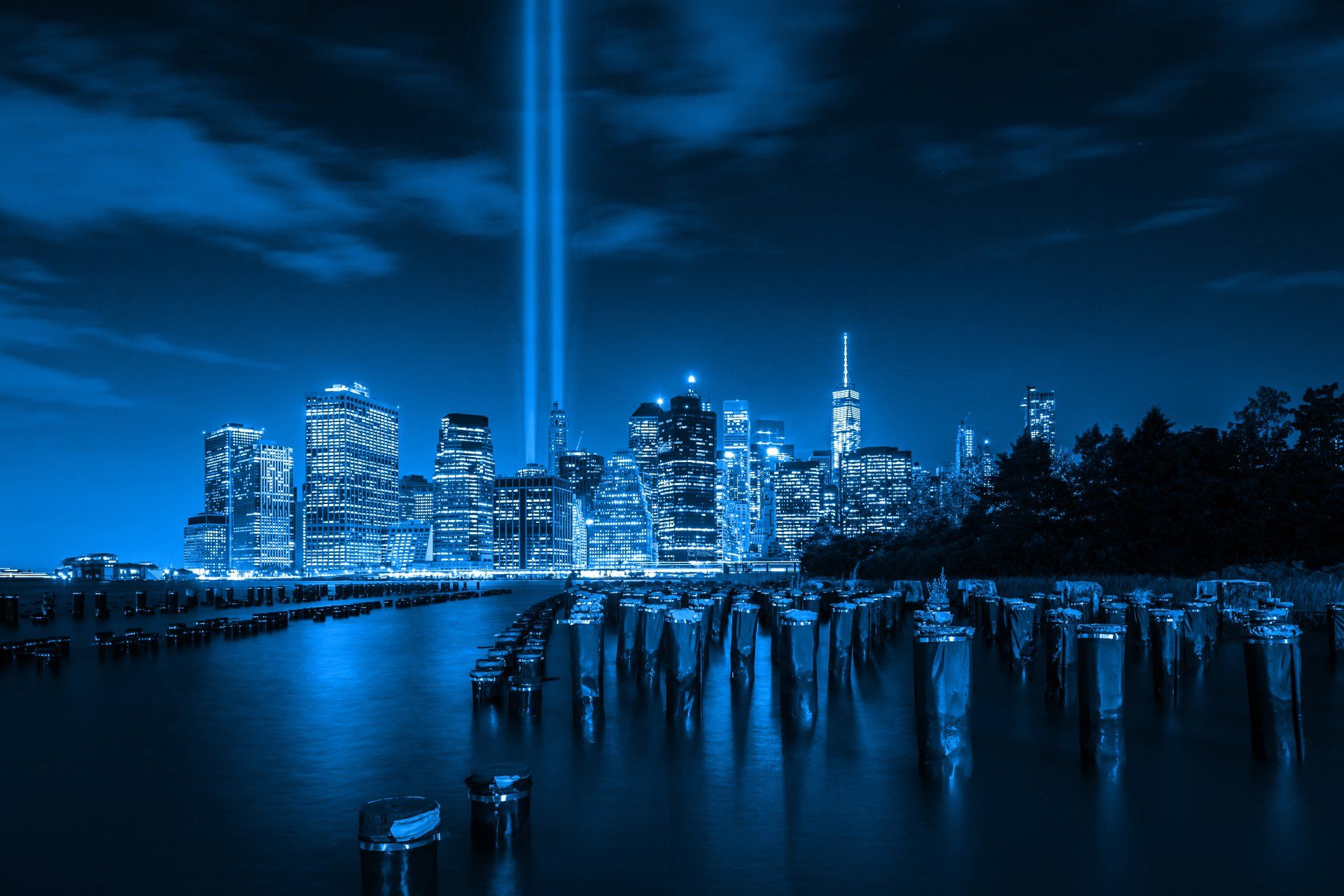 A city skyline at night with a blue light coming out of the sky