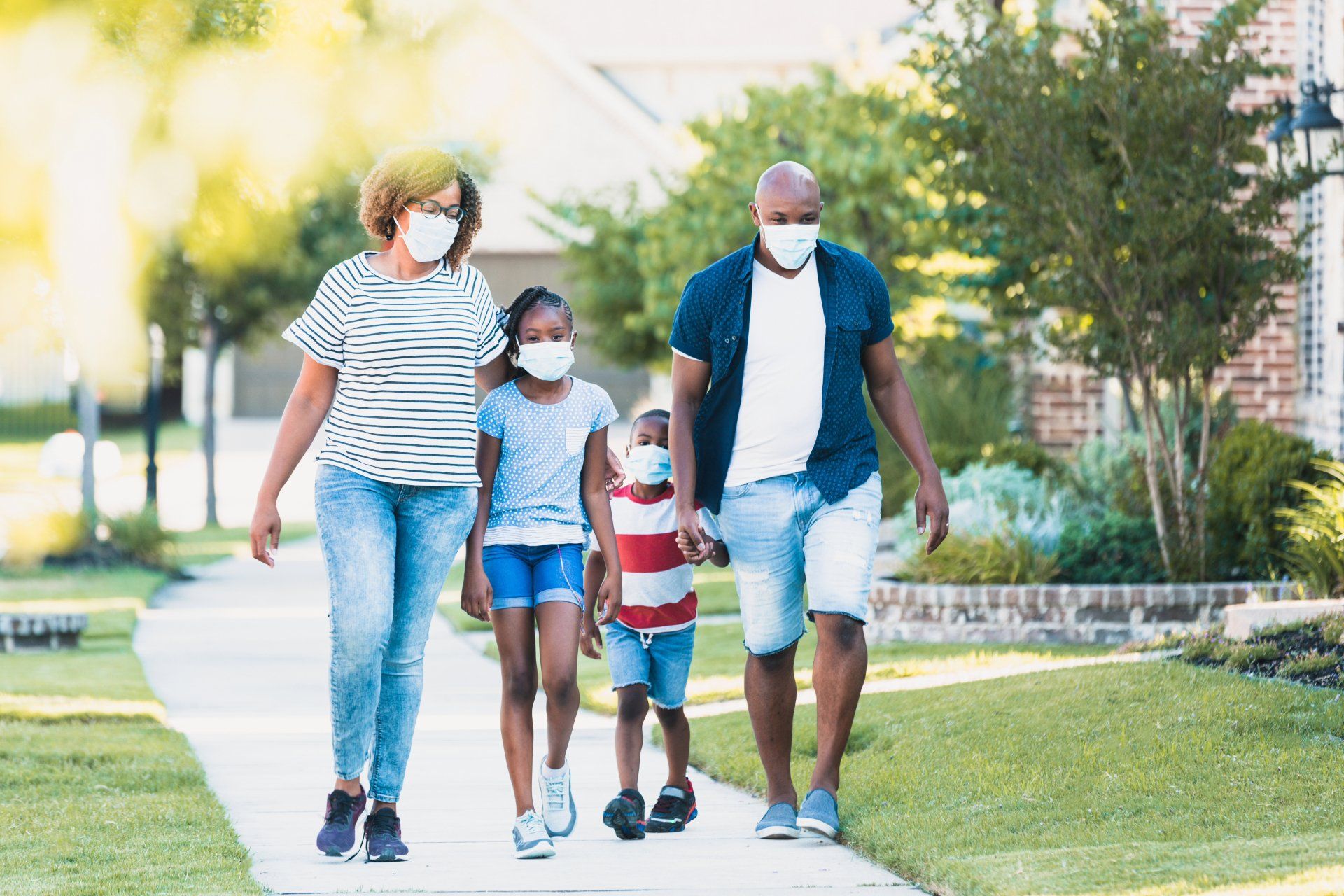 A family wearing face masks is walking down a sidewalk.