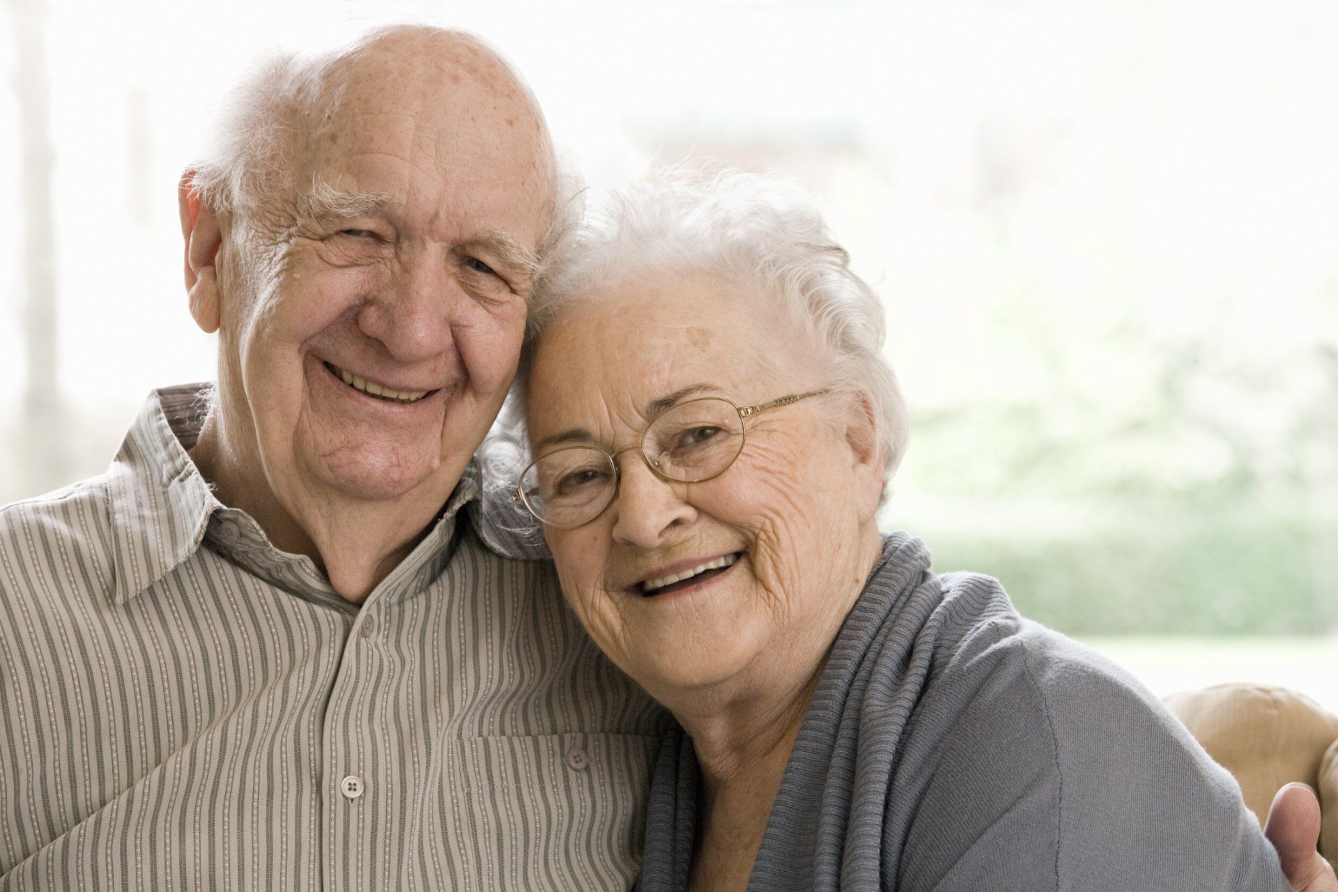 An elderly couple is posing for a picture together and smiling.
