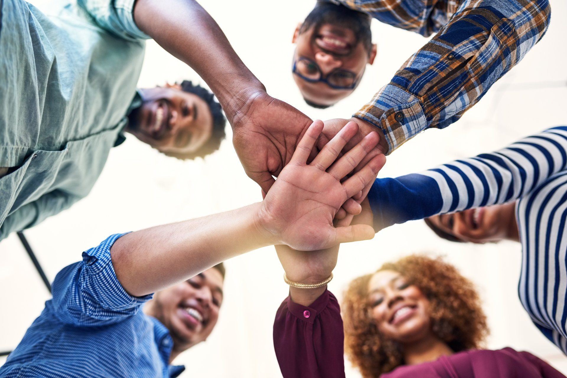 A group of people are putting their hands together in a circle.