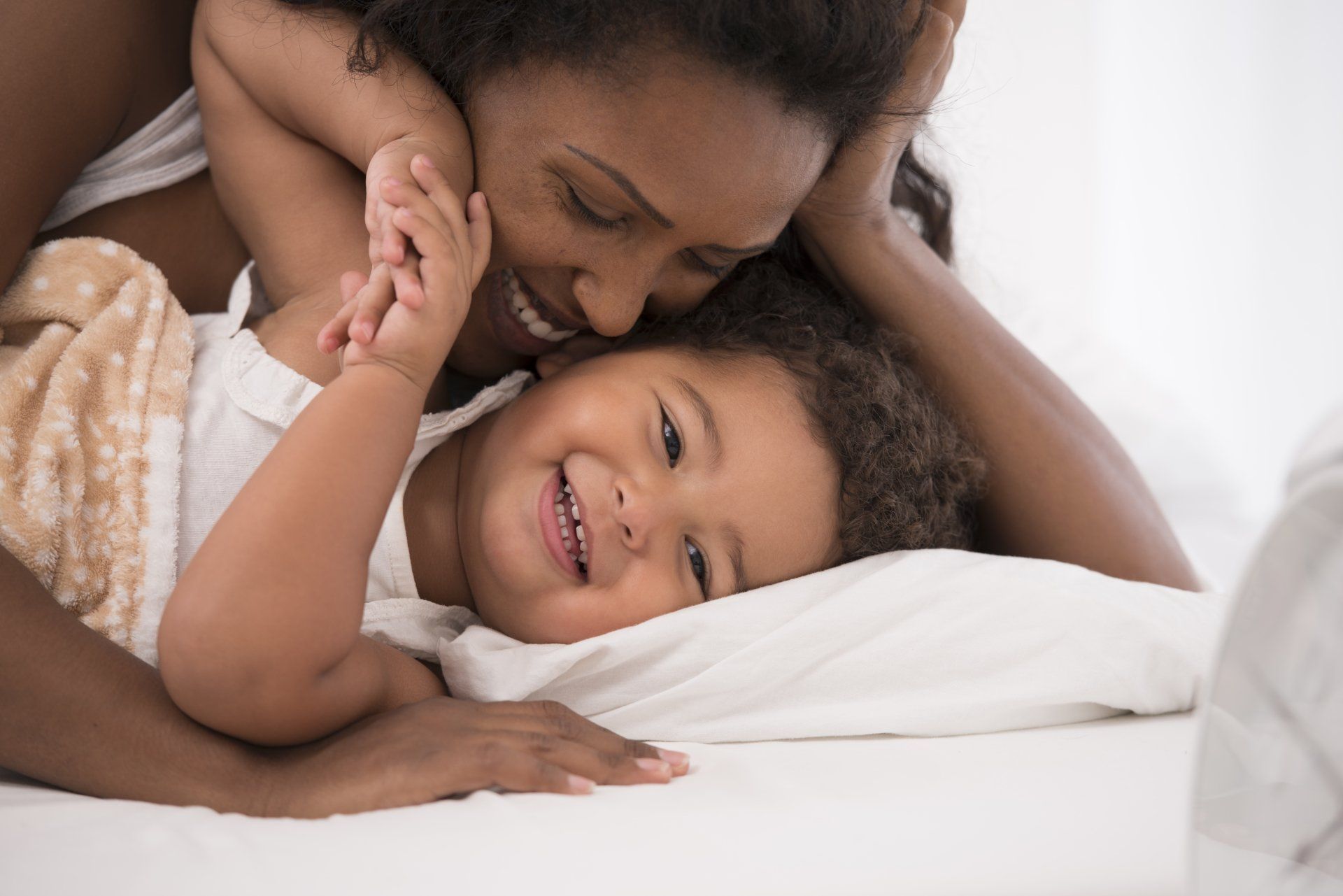 A woman is laying on a bed with a child.