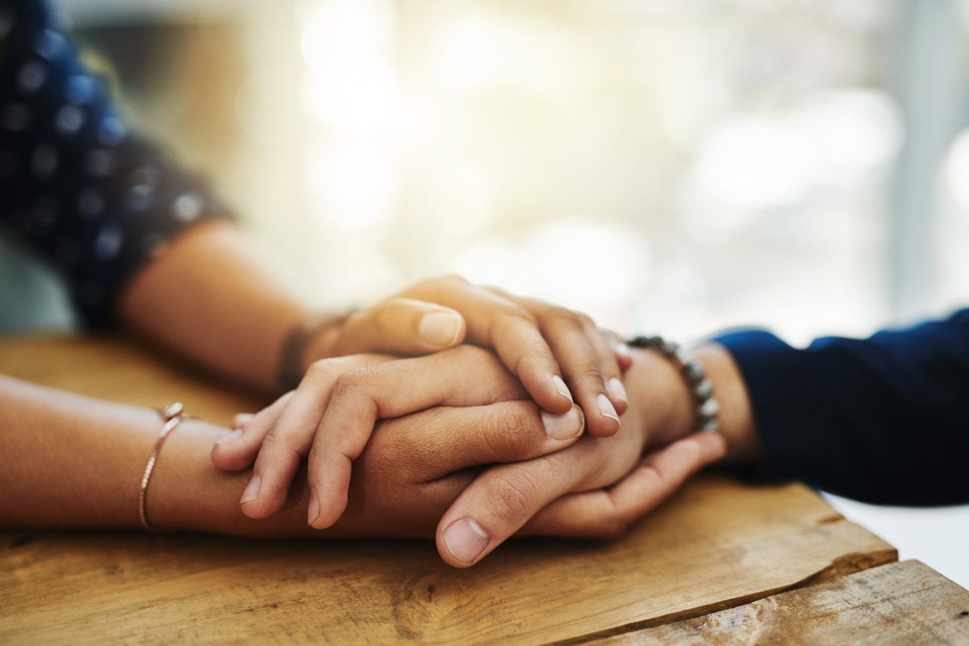 A man and a woman are holding hands on a wooden table.