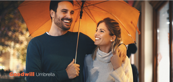 A man and a woman are holding an orange umbrella.