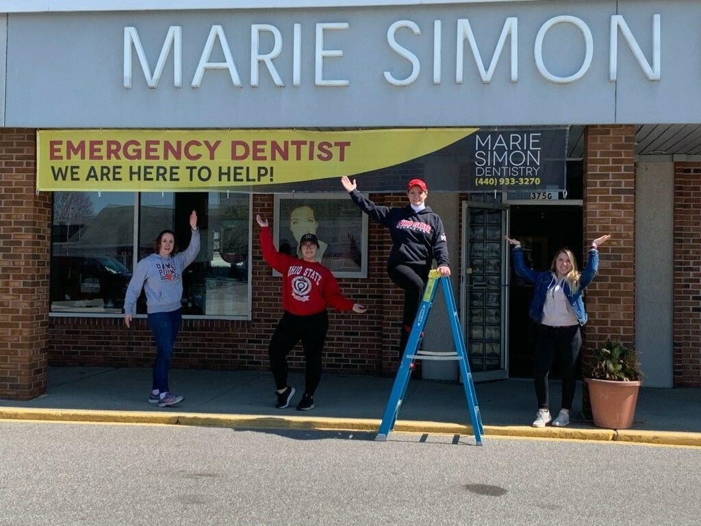 A group of people are standing in front of a marie simon emergency dentist office.