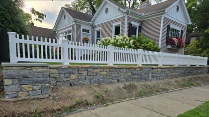 A person is using a drill to install a wooden fence.