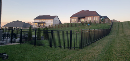 A man wearing red gloves and a tool belt is working on a wooden fence.