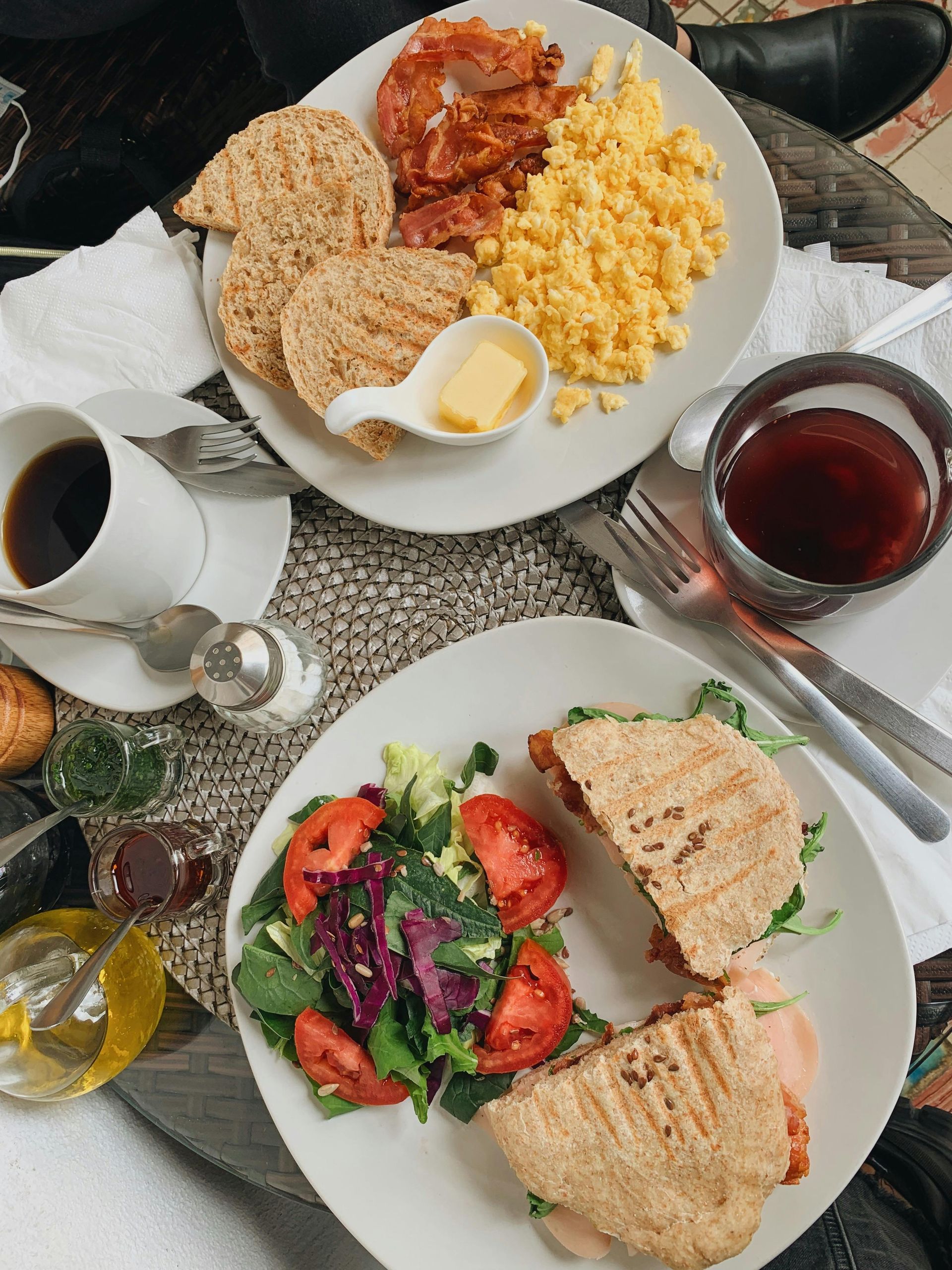 Breakfast plates: scrambled eggs, bacon, toast, panini sandwich, salad, coffee, and tea.