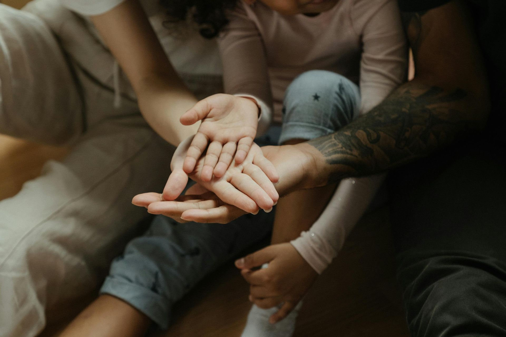 Hands stacked together; adult, child, and another adult showing unity.