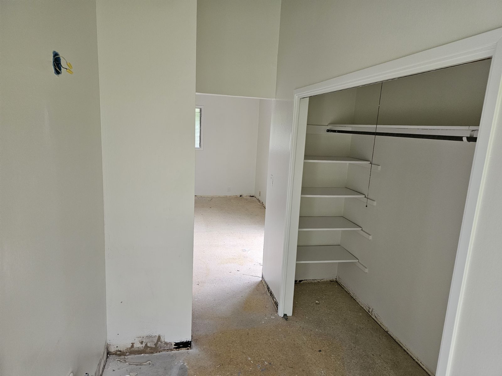 A closet with shelves and a hanging rail in a room.