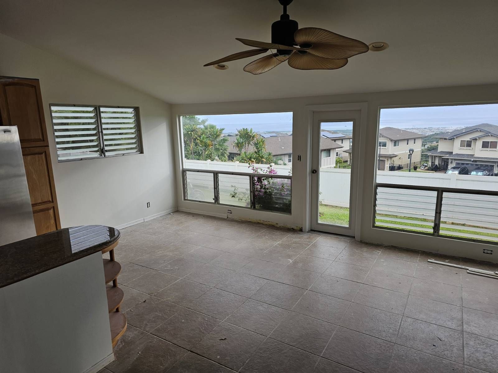 A living room with a ceiling fan and lots of windows