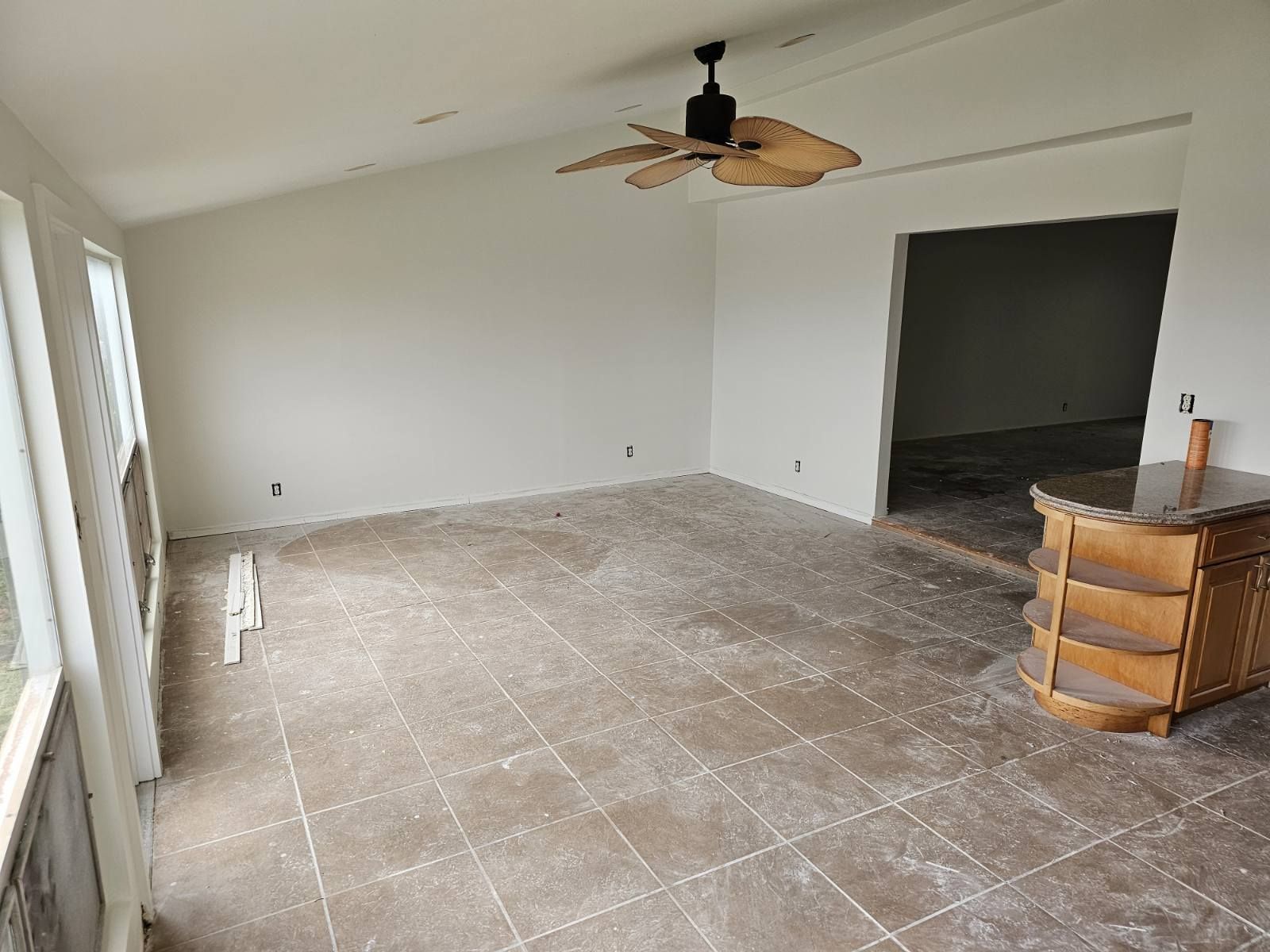 An empty room with tile floors and a ceiling fan