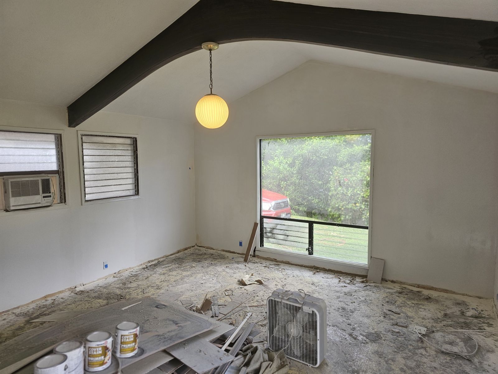 An empty room with a large window and a light hanging from the ceiling.