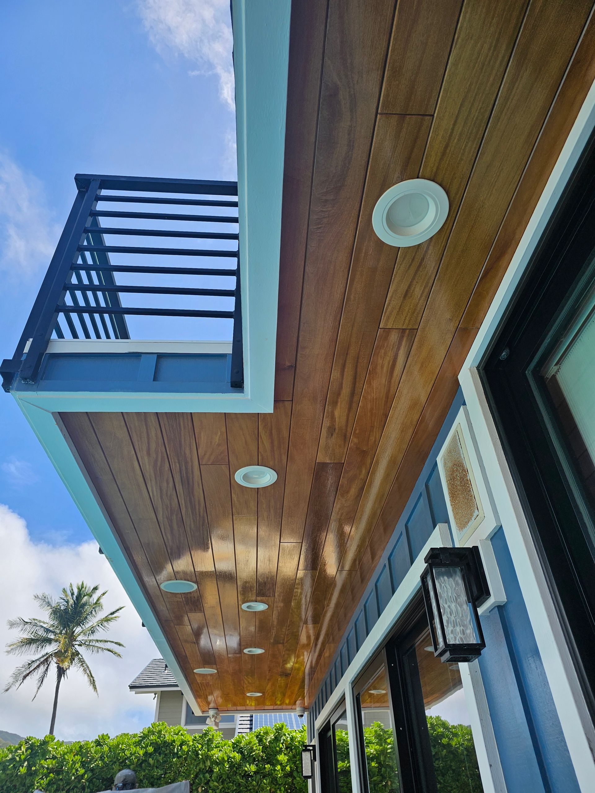 The ceiling of a house with a balcony and a palm tree in the background.