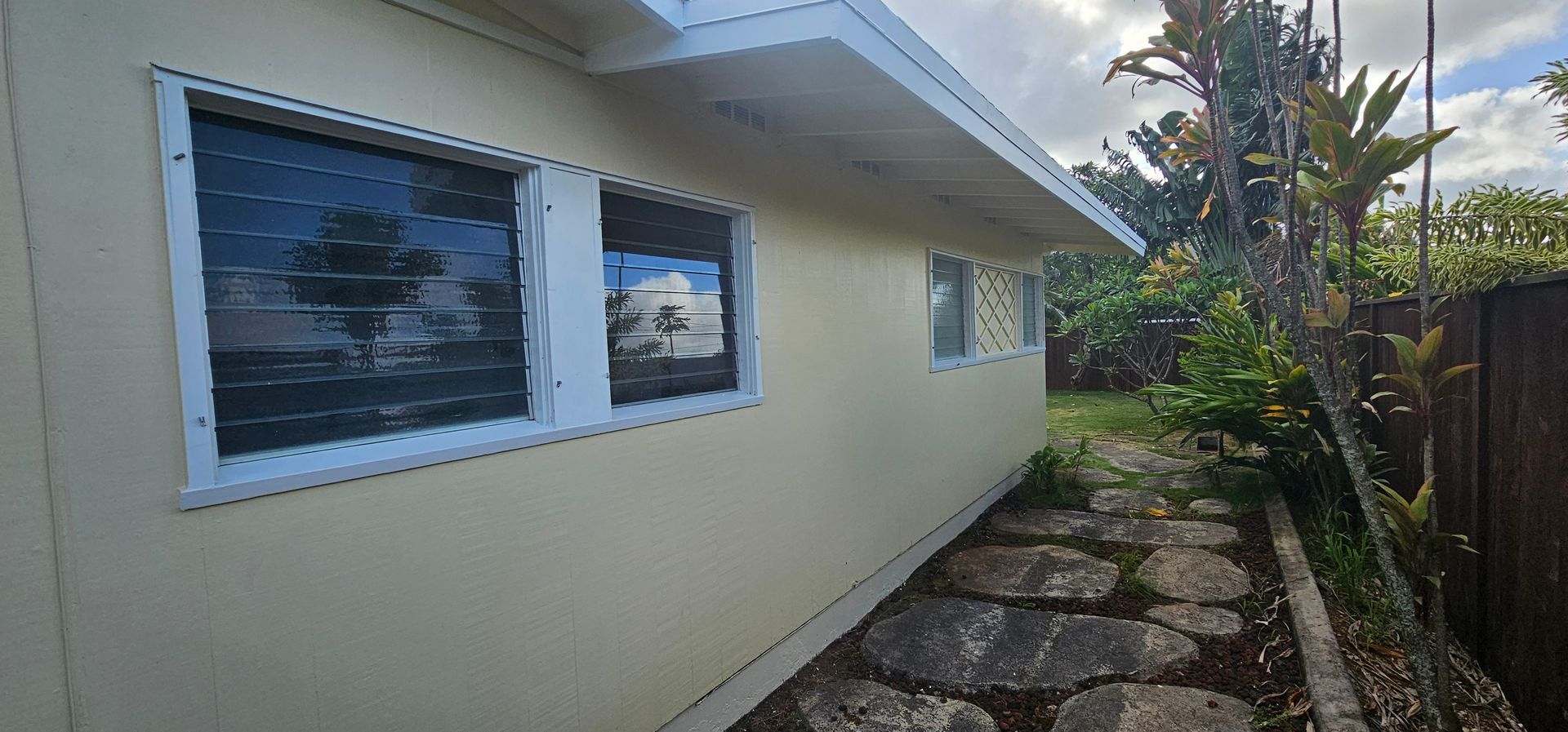 A house with a lot of windows and a stone path leading to it.