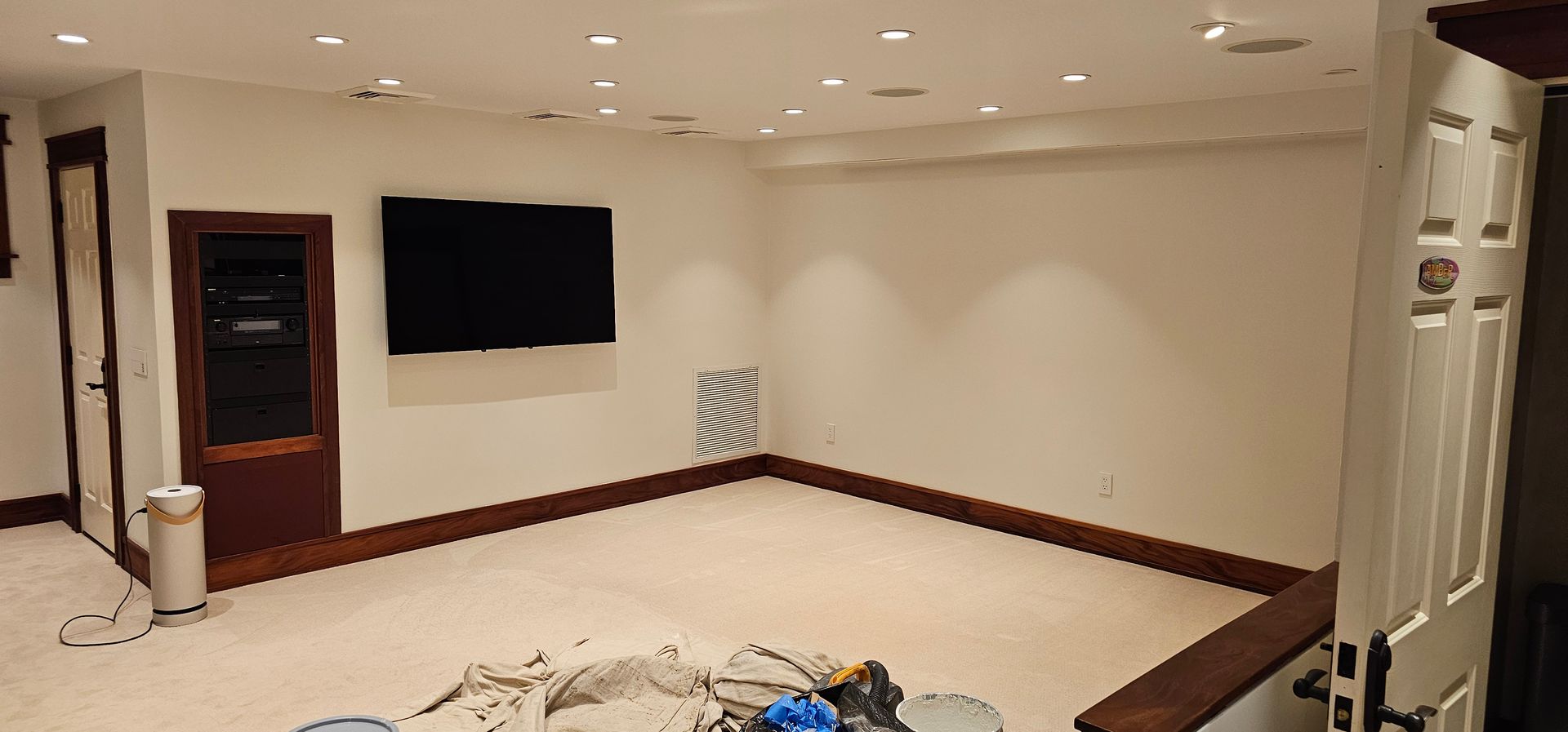 An empty basement with a flat screen tv on the wall.