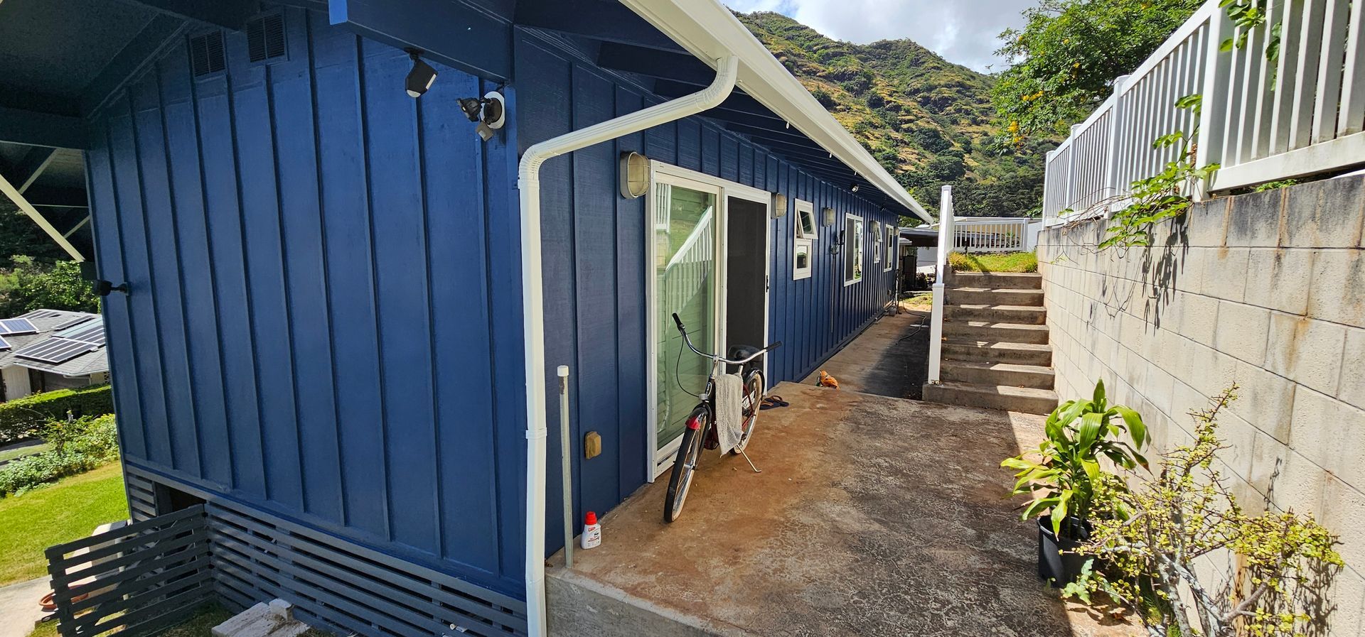 A blue house with a bicycle parked in front of it.