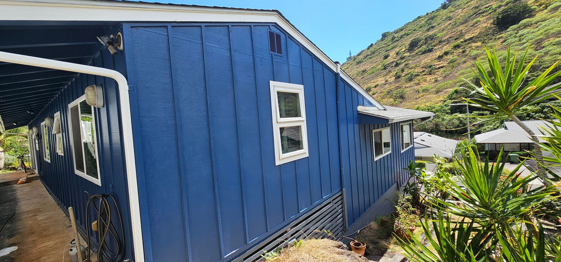 A blue house with white trim is sitting on top of a hill.