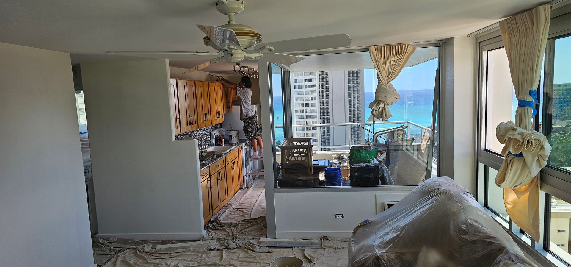 A living room with a ceiling fan and a view of the ocean.