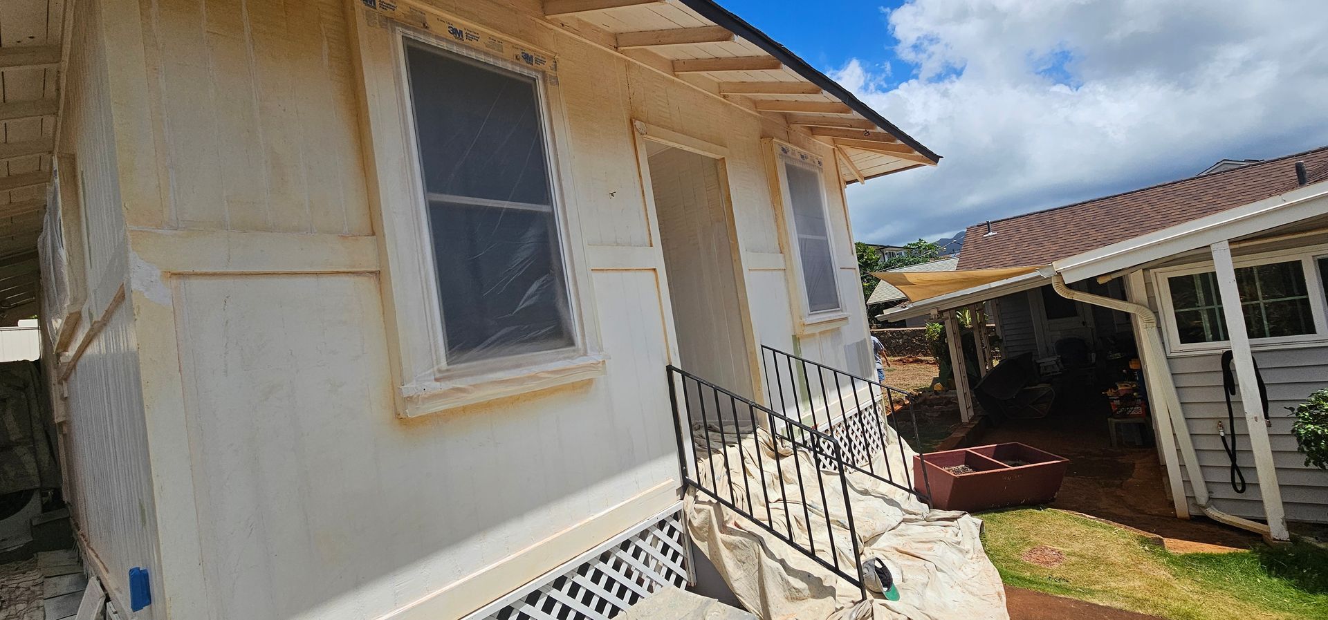 A white house with a balcony and stairs is being painted white.