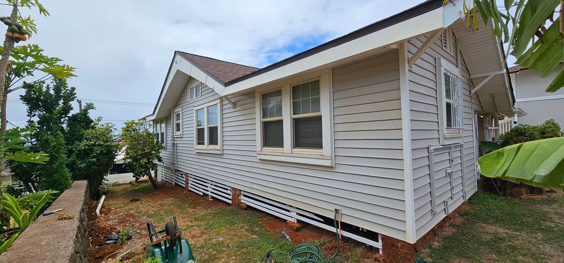 A small white house with a red roof is sitting on top of a lush green field.
