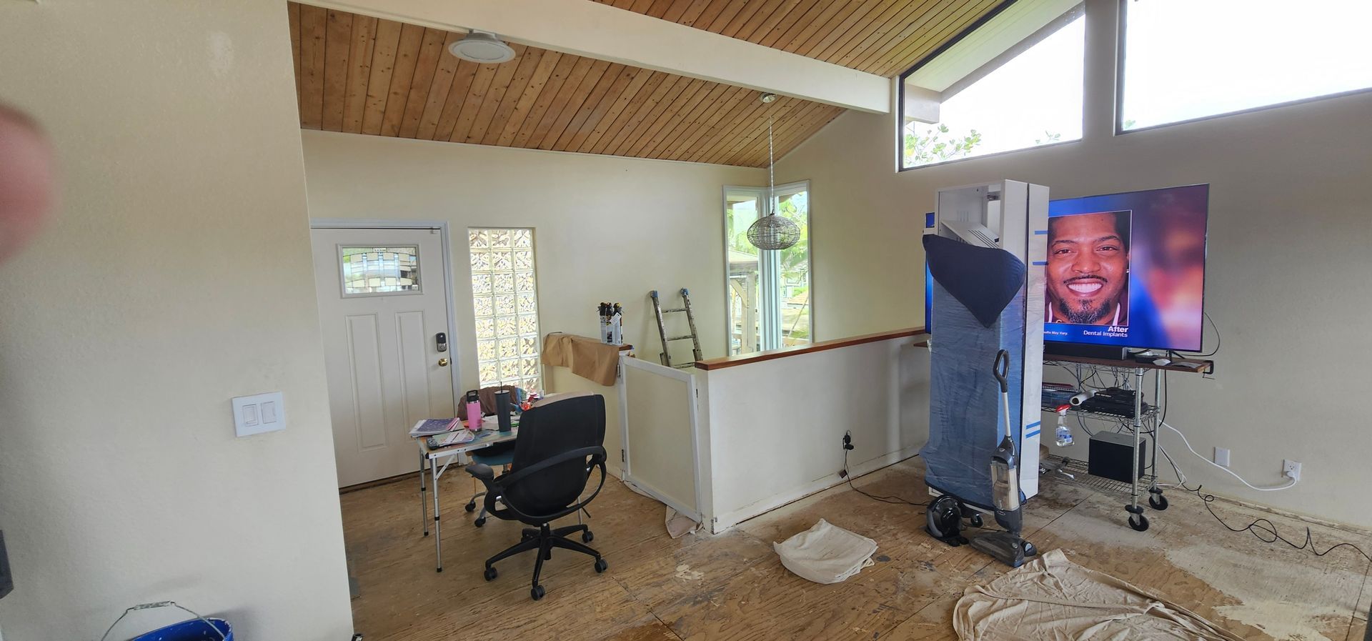 A living room with a desk , chair and television.