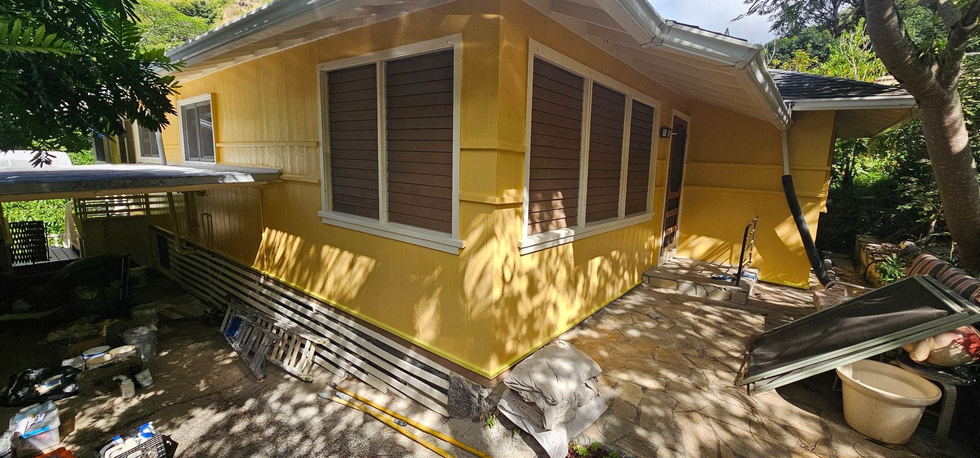 A yellow house with a lot of windows is being painted.