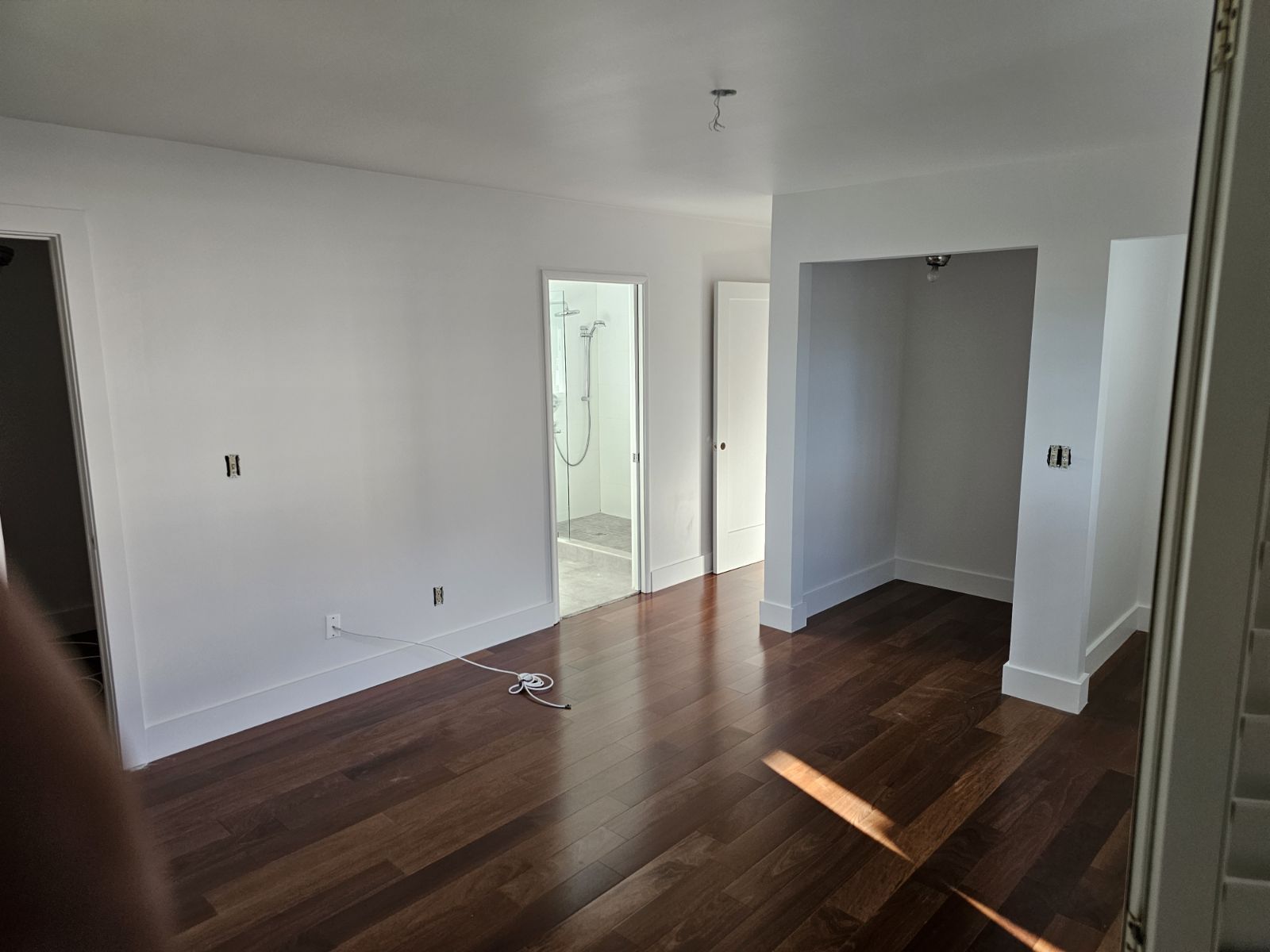 A large empty room with hardwood floors and white walls.