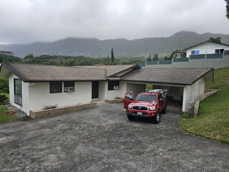 A red truck is parked in front of a white house
