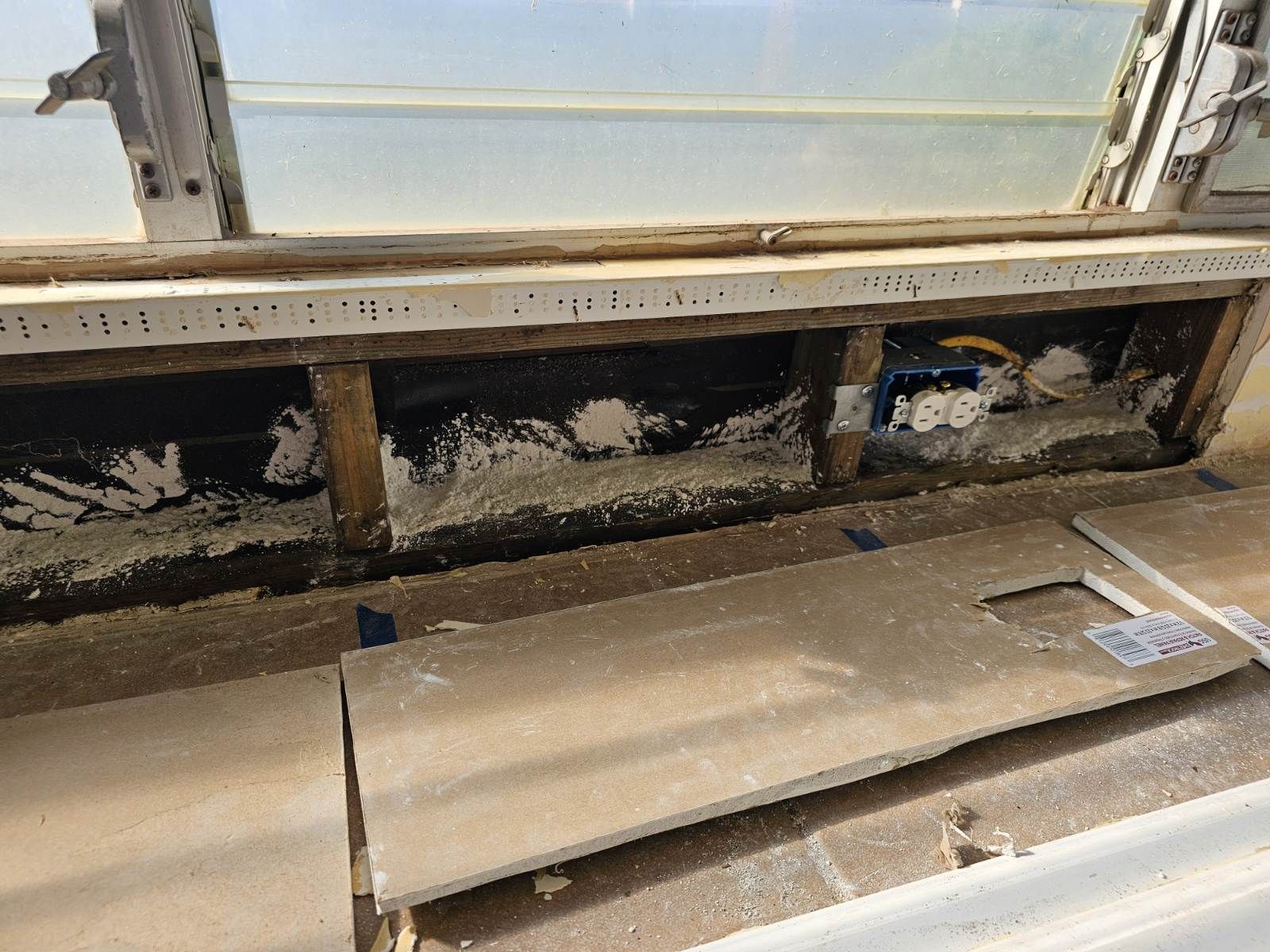 A wooden box is sitting on top of a wooden floor next to a window.