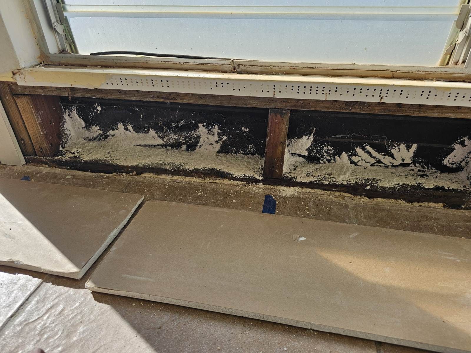 A room with a window and a piece of wood on the floor.