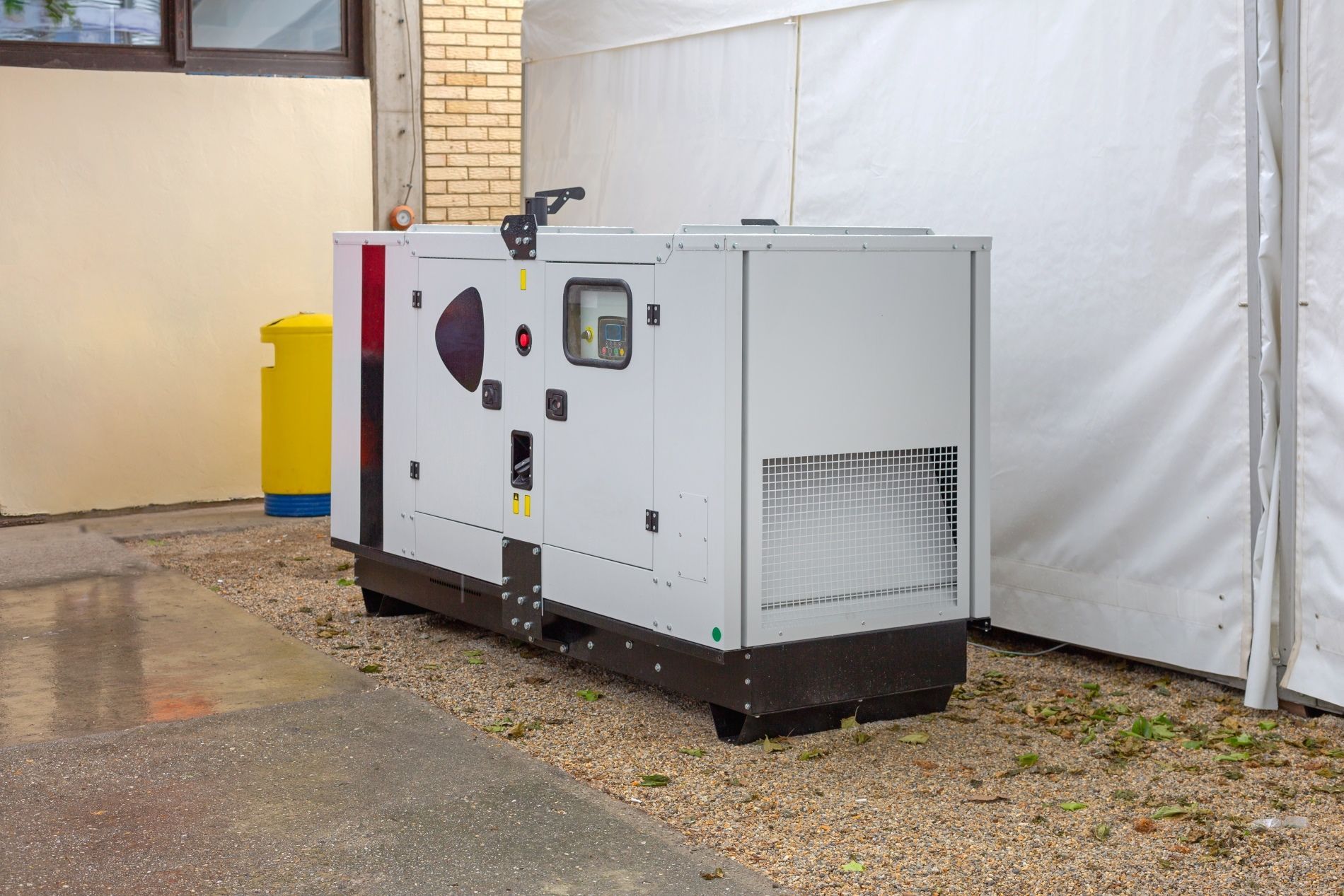 A large white generator is sitting outside of a building.