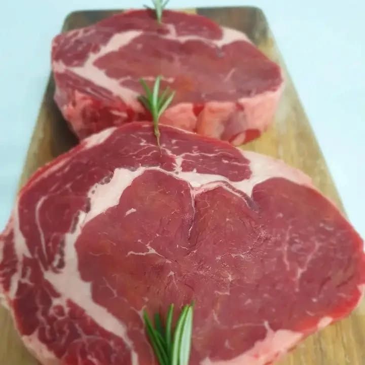 Two Raw Steaks With Rosemary on a Wooden Cutting Board — Multy Cut Meats In Yorkeys Knob, QLD