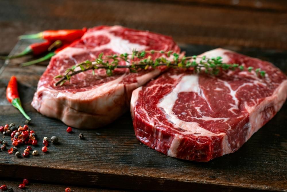 Two Raw Steaks Are Sitting on a Wooden Cutting Board — Multy Cut Meats In Cooktown, QLD