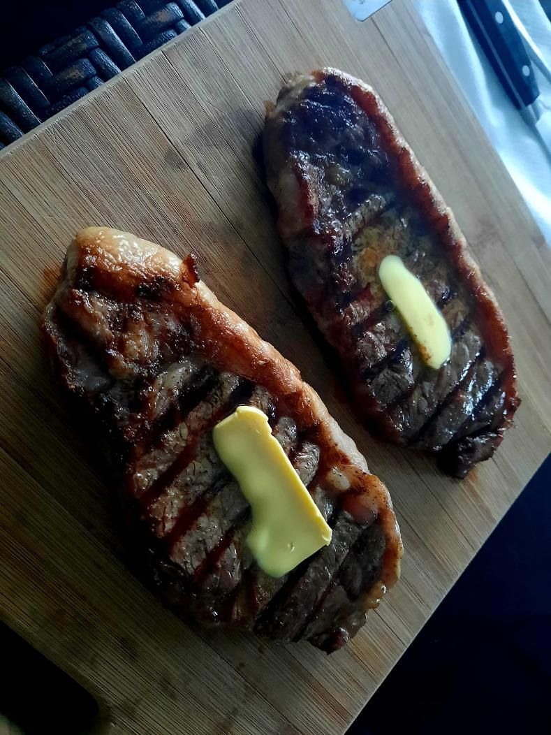 Two Steaks With Butter on Them on a Wooden Cutting Board — Multy Cut Meats In Yorkeys Knob, QLD