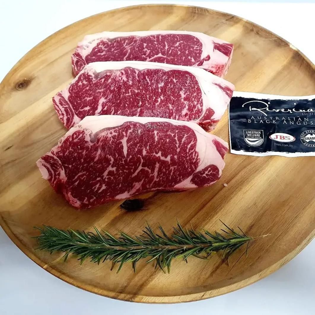 Three Steaks Are Sitting on a Wooden Cutting Board — Multy Cut Meats In Yorkeys Knob, QLD