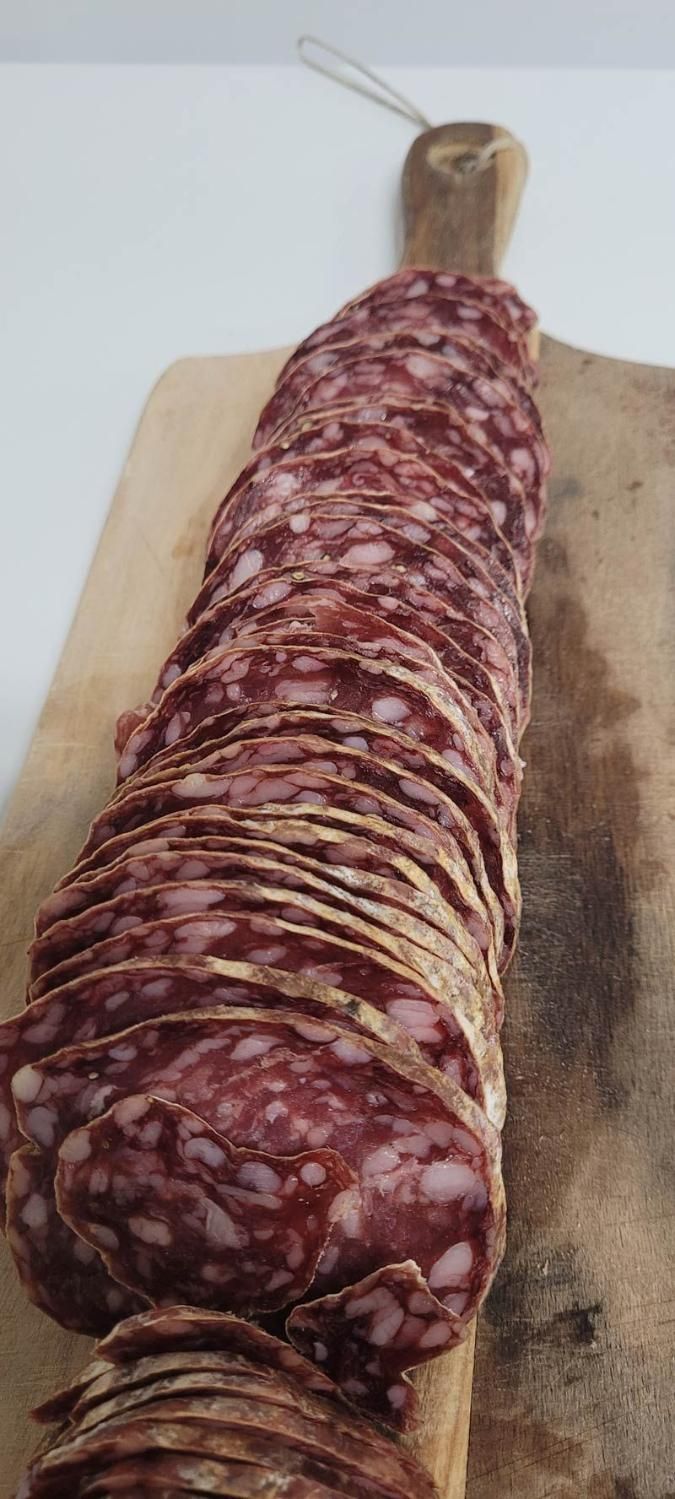 A lOng Piece of Salami is Sitting on a Wooden Cutting Board — Multy Cut Meats In Yorkeys Knob, QLD