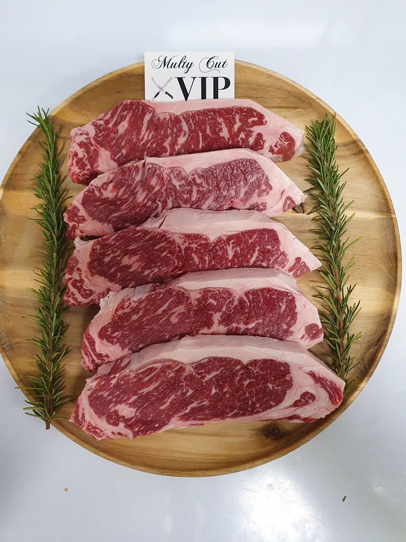 A Wooden Plate Topped With Steaks and Rosemary — Multy Cut Meats In Yorkeys Knob, QLD