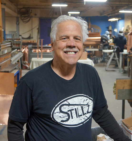 A man is sitting in a chair talking to another man in a room.