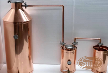 A copper still is sitting on a white table