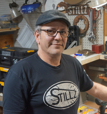 A man wearing glasses and a black shirt that says stillz