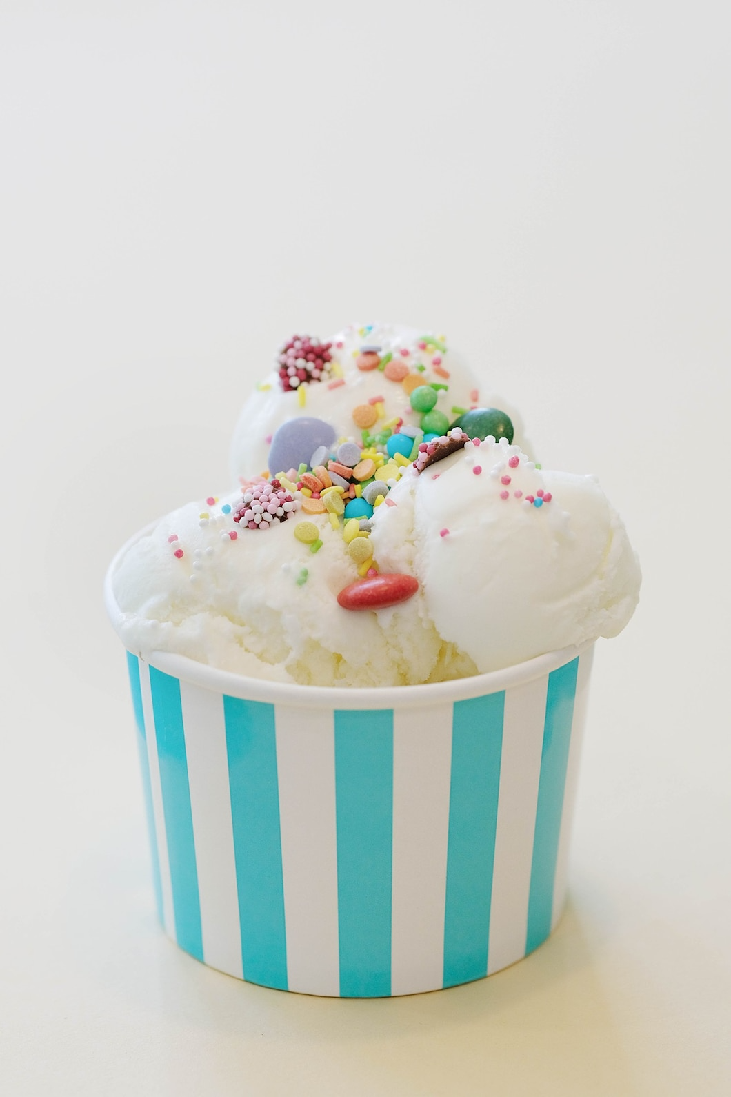 A cup of ice cream with sprinkles and marshmallows on top.