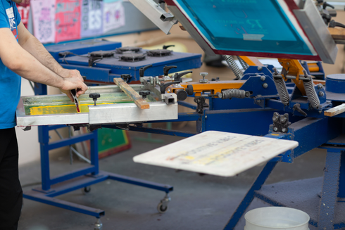 Un hombre está trabajando en una máquina de serigrafía en una fábrica.