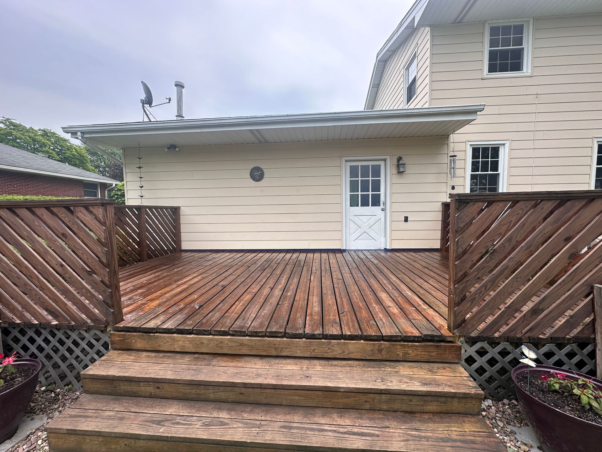 A wooden deck with stairs leading up to it is in front of a house.