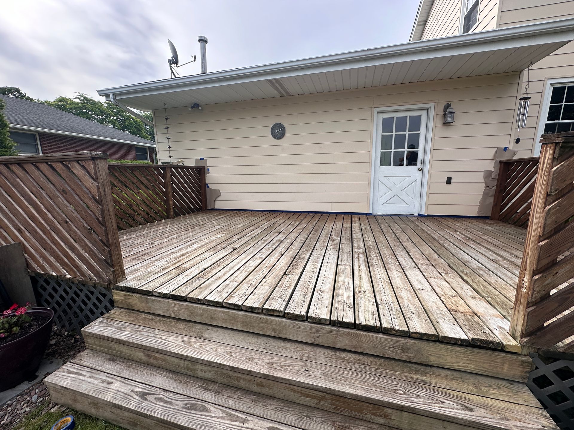A wooden deck with stairs leading up to it is in front of a house.