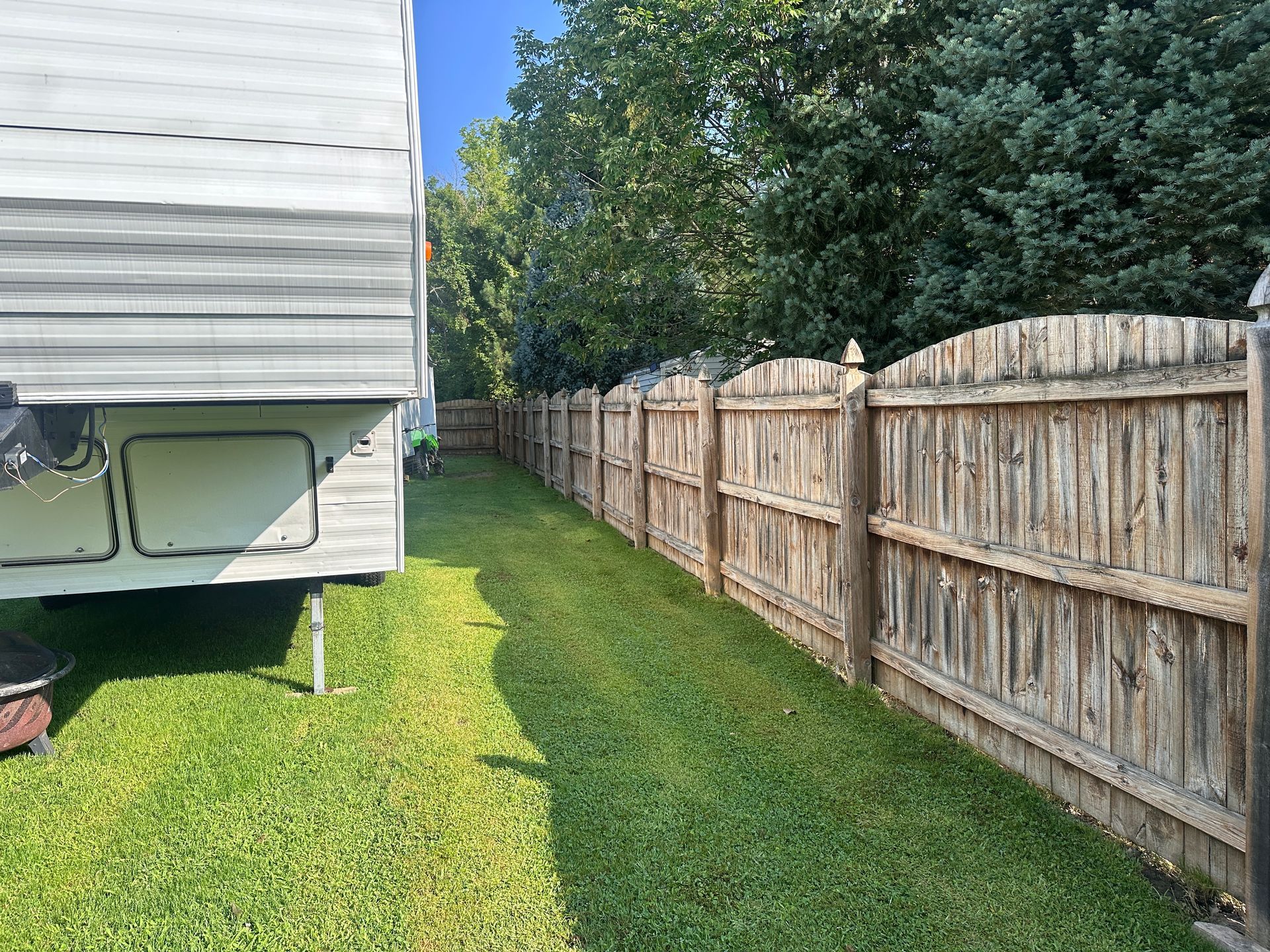 A trailer is parked next to a wooden fence.