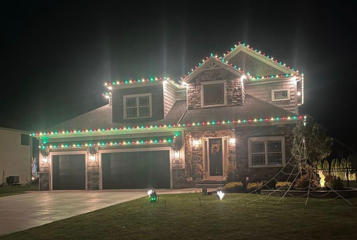 A large house is decorated with christmas lights at night.