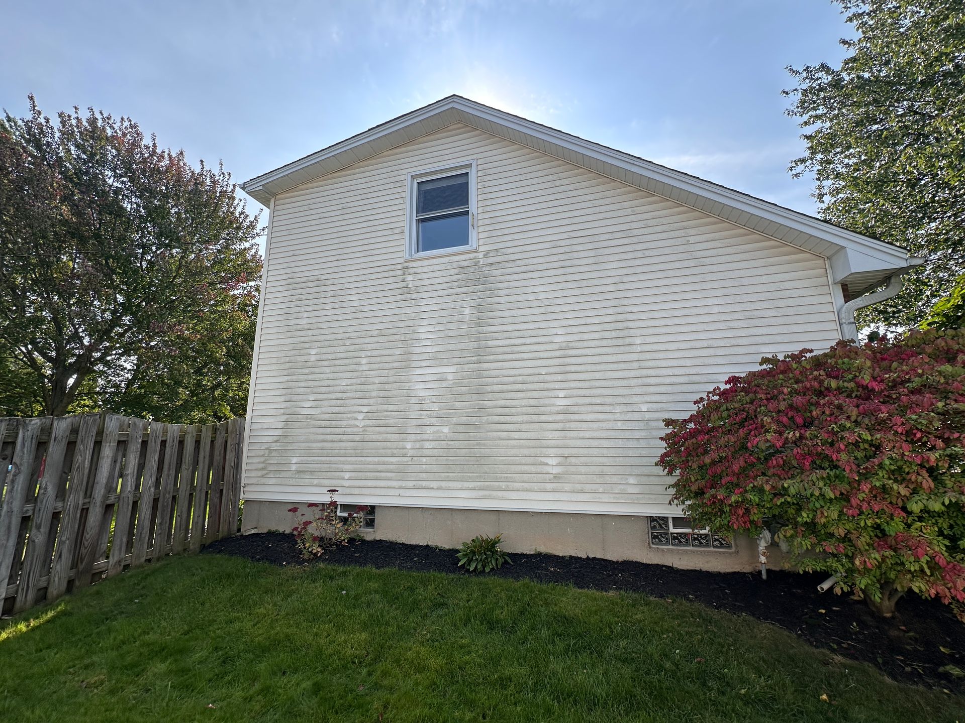 A white house with a wooden fence in the backyard.
