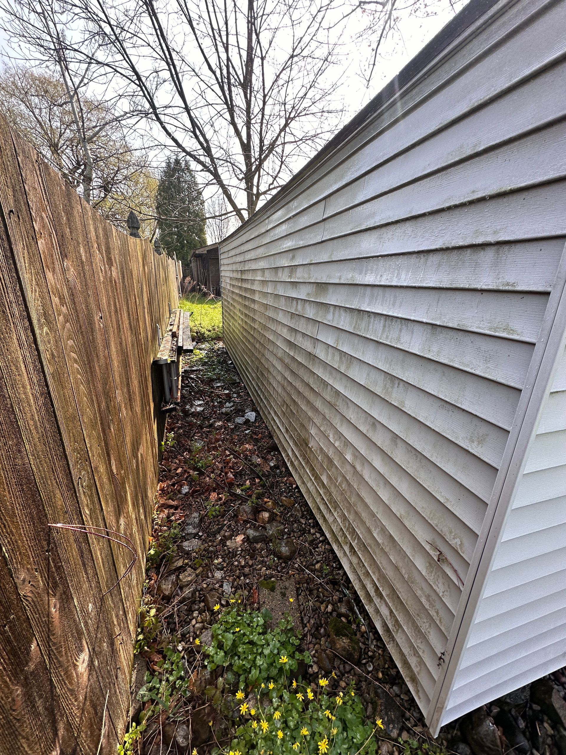 A mobile home is leaning against a fence in the backyard.